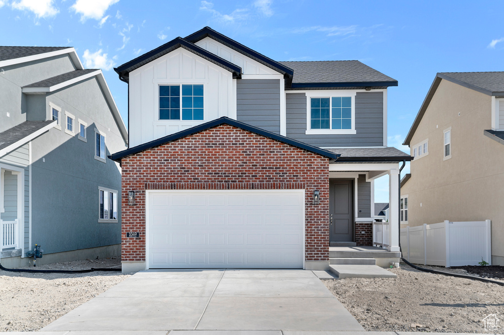 View of front of home with brick siding, concrete driveway, board and batten siding, and an attached garage