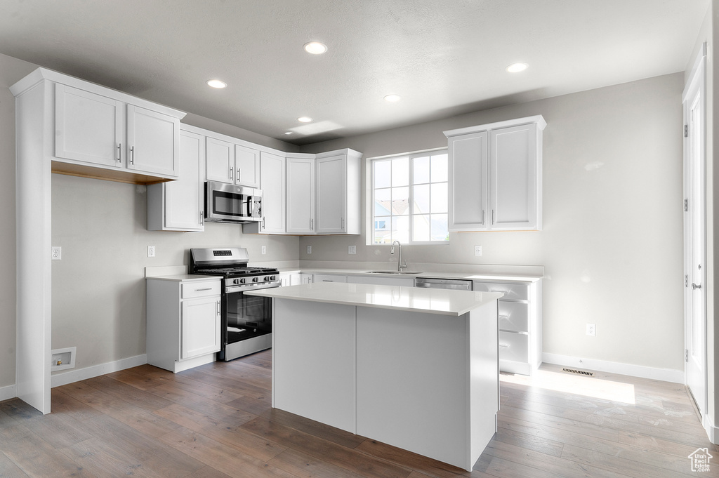 Kitchen featuring appliances with stainless steel finishes, a sink, baseboards, recessed lighting, and light countertops