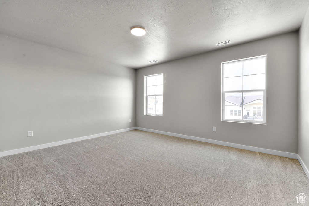 Unfurnished room with a textured ceiling, baseboards, and light carpet