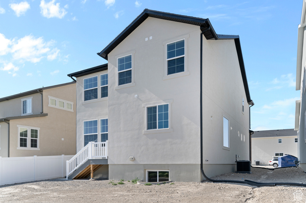 Rear view of property with stucco siding and central AC unit