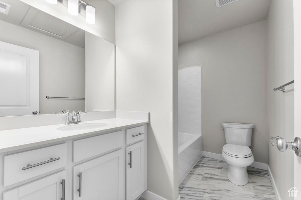 Full bath featuring toilet, vanity, marble finish floors, and baseboards