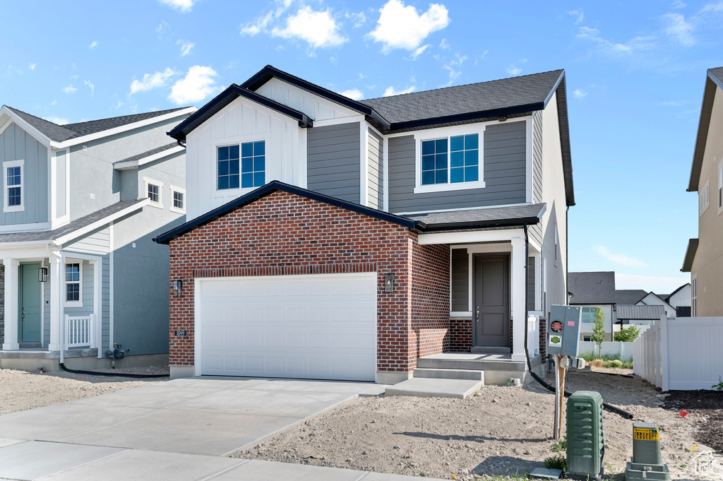View of front of house with brick siding, driveway, board and batten siding, an attached garage, and a shingled roof