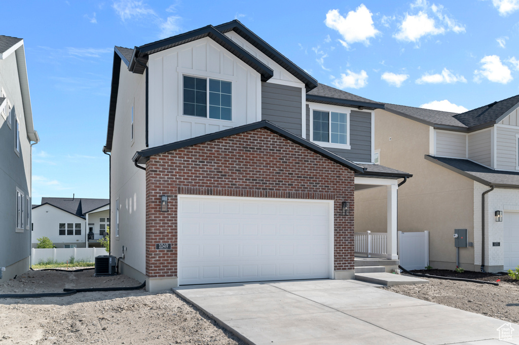 View of front facade with brick siding, board and batten siding, concrete driveway, and central air condition unit