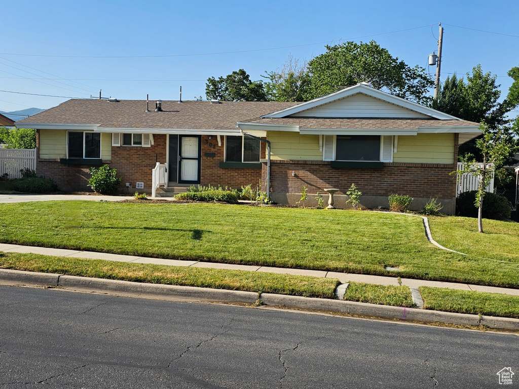 Ranch-style house with brick siding, concrete driveway, a front yard, and a garage