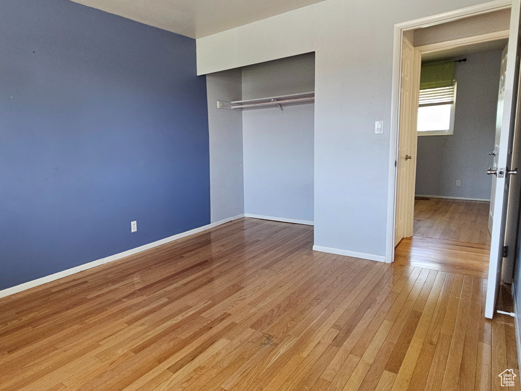 Unfurnished bedroom with wood finished floors and a closet