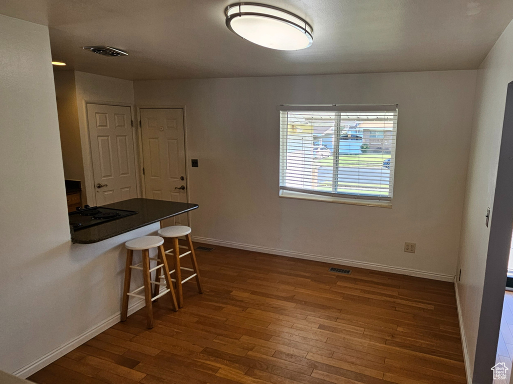 Unfurnished dining area with dark wood-style floors and baseboards
