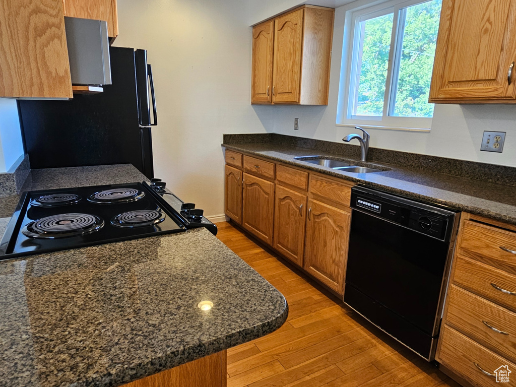 Kitchen featuring black appliances, light wood finished floors, and brown cabinets