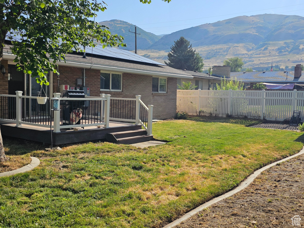 Fenced backyard with a deck with mountain view