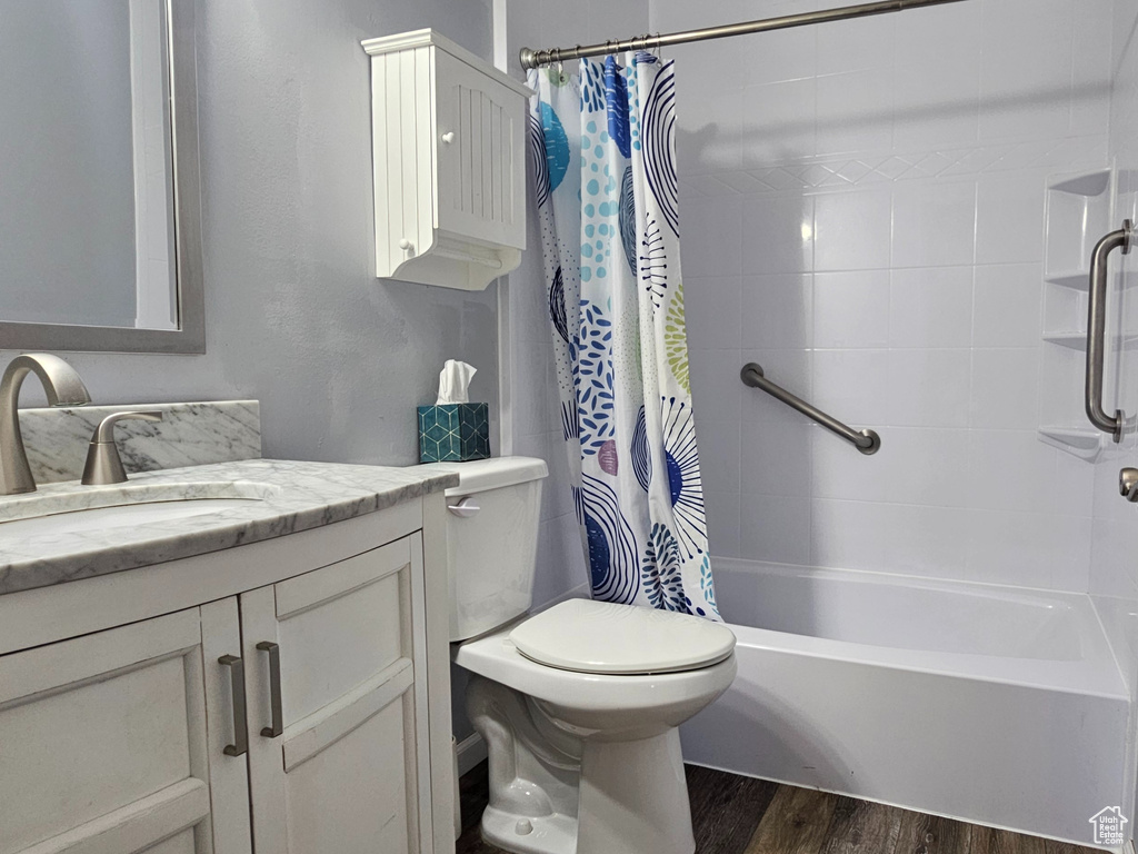 Bathroom featuring vanity, wood finished floors, and shower / bathtub combination with curtain