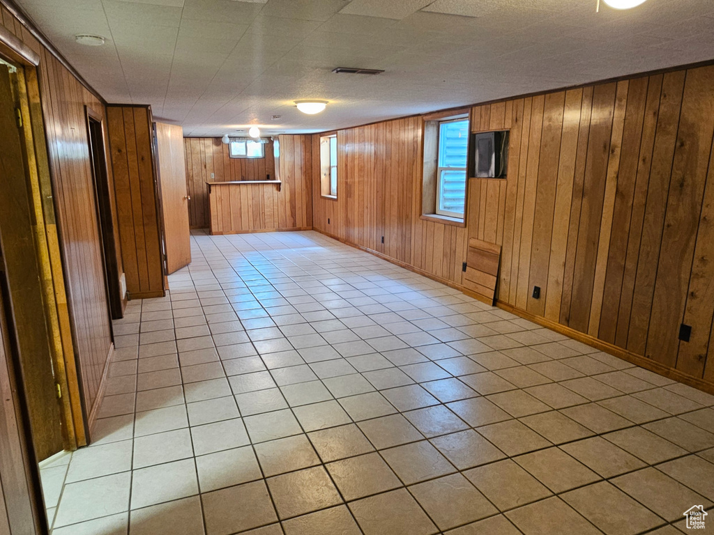 Unfurnished room with light tile patterned flooring and wood walls