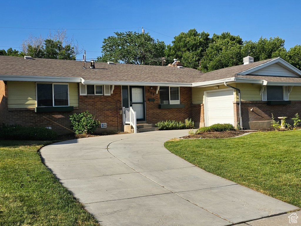 Single story home featuring an attached garage, brick siding, concrete driveway, and a chimney