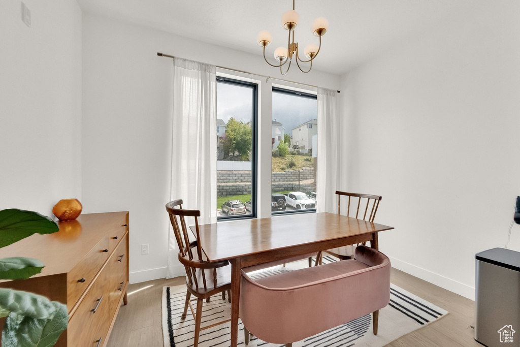 Dining room featuring light wood-style floors, baseboards, and a chandelier