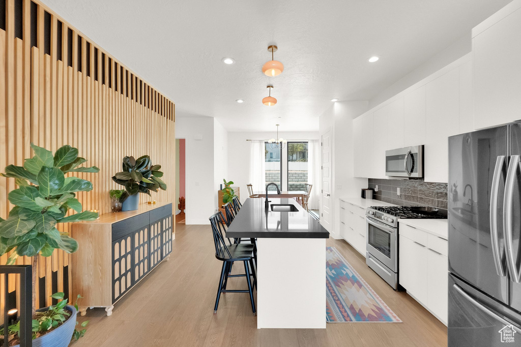 Kitchen featuring backsplash, appliances with stainless steel finishes, modern cabinets, a sink, and white cabinets