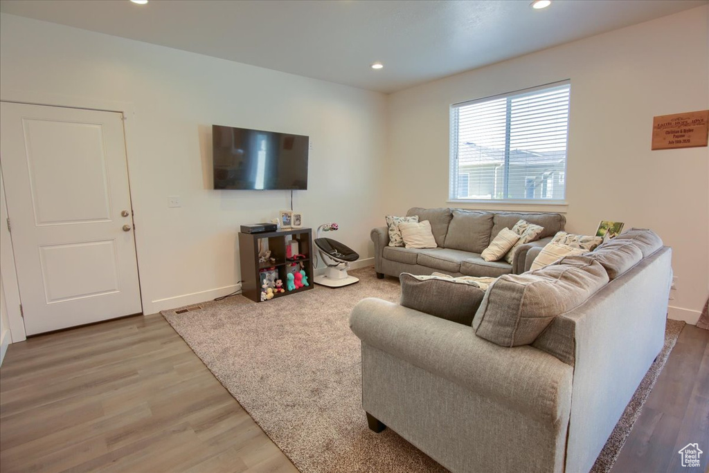 Living area with baseboards, recessed lighting, and light wood-style flooring