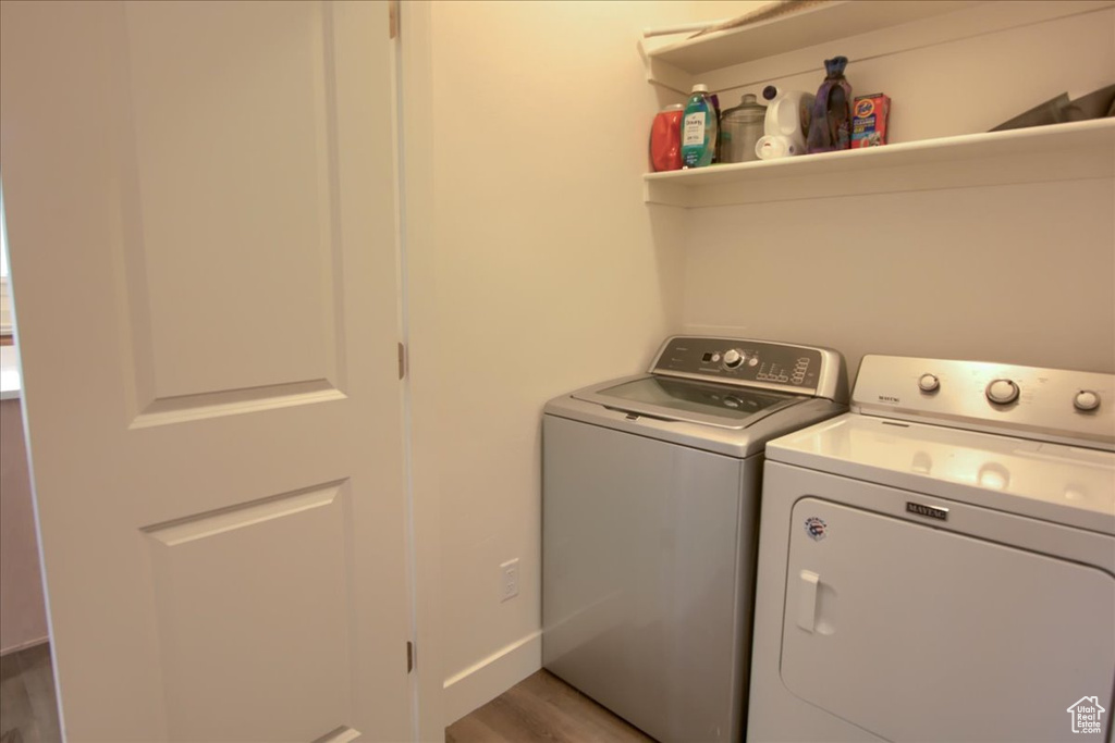 Laundry room with laundry area, washer and clothes dryer, and light wood-style floors