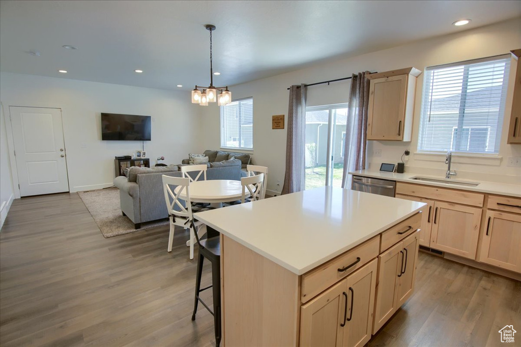 Kitchen with stainless steel dishwasher, wood finished floors, a sink, and light brown cabinets
