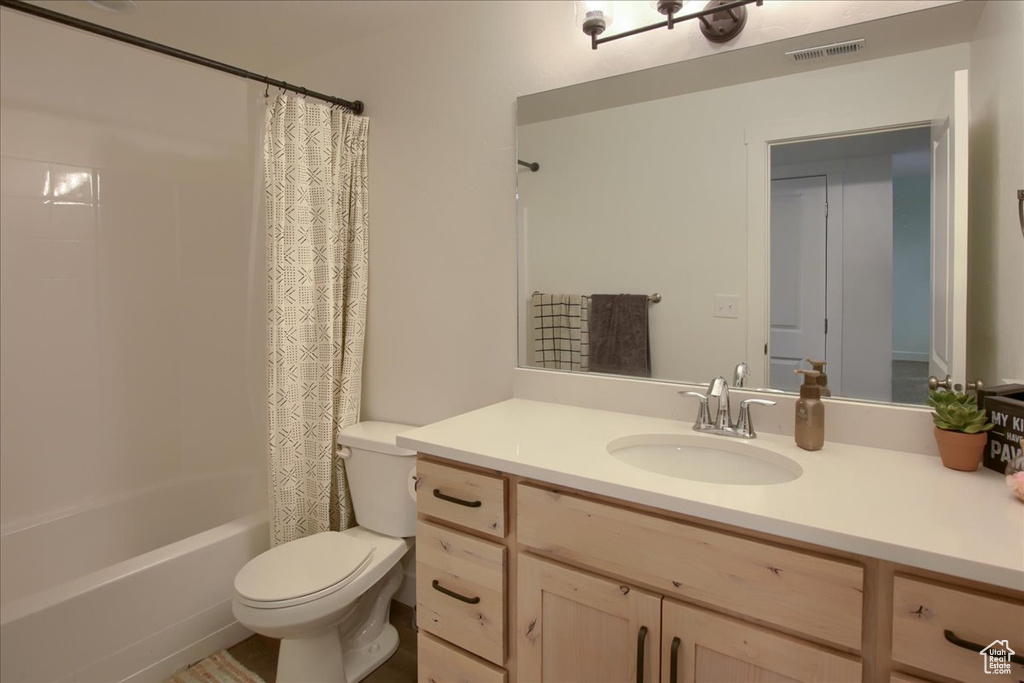 Bathroom with vanity, shower / bath combo, toilet, and visible vents