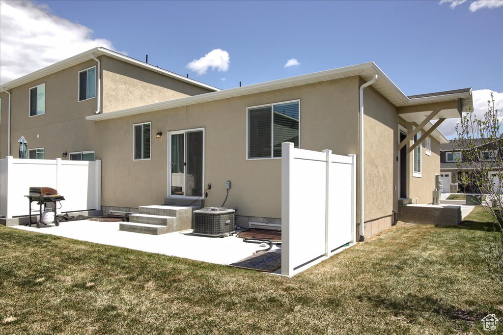 Rear view of house featuring fence, stucco siding, a lawn, and a patio area