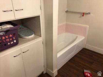 Bathroom with baseboards, a garden tub, and wood finished floors