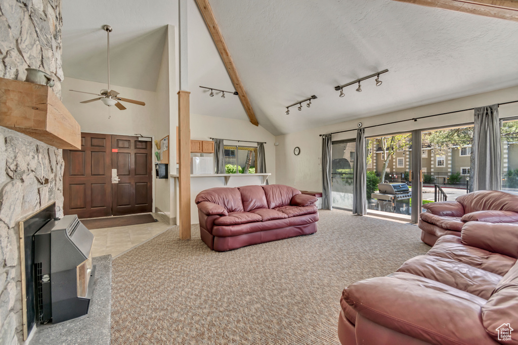 Carpeted living room featuring ceiling fan, a fireplace, track lighting, high vaulted ceiling, and beamed ceiling