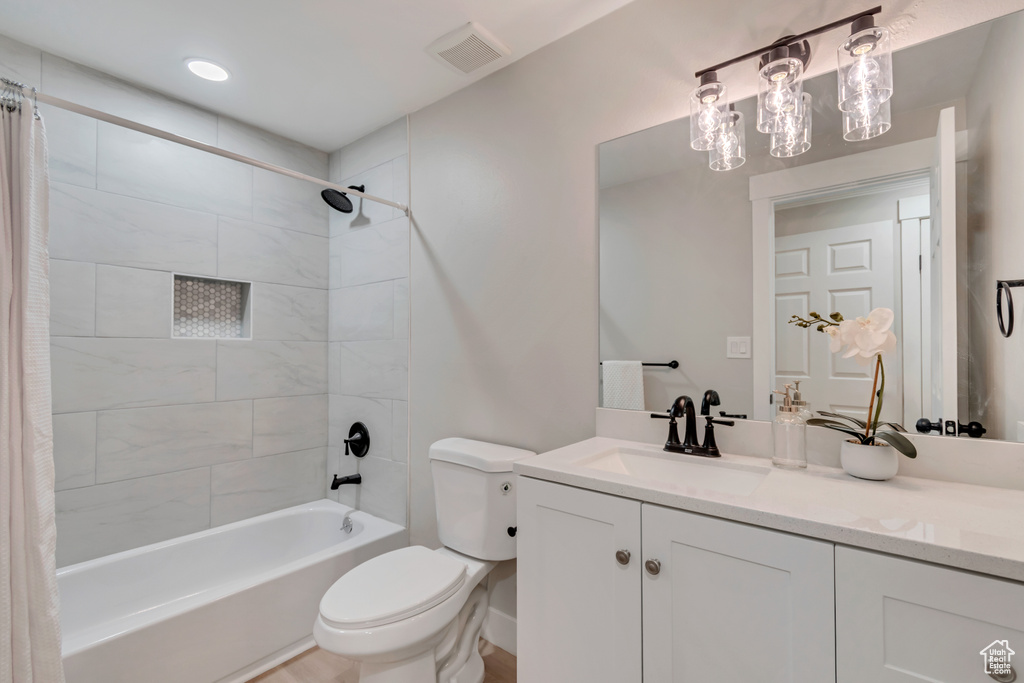 Full bathroom featuring vanity, shower / bath combo, toilet, and visible vents