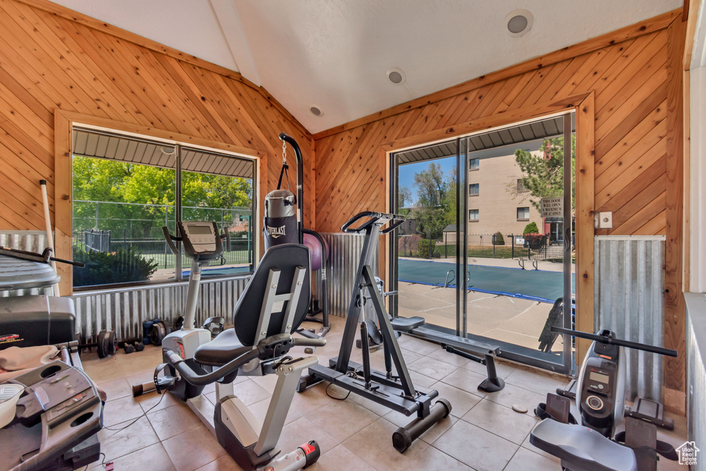 Exercise area featuring lofted ceiling, wood walls, and a wealth of natural light