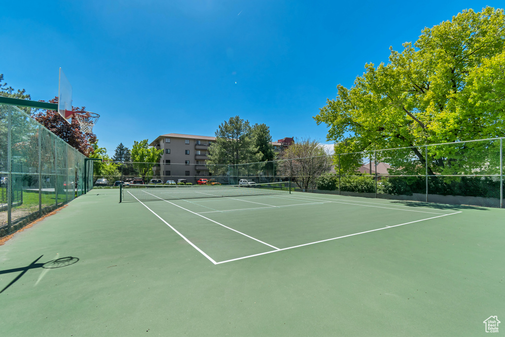 View of tennis court featuring fence and community basketball court