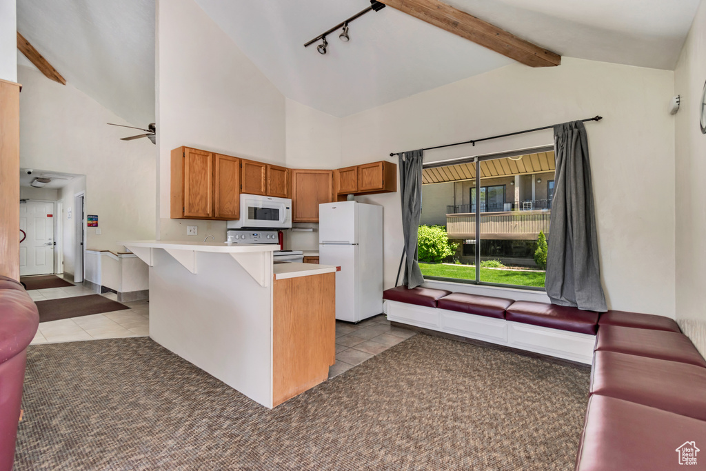 Kitchen featuring tile patterned flooring, track lighting, a peninsula, a breakfast bar, and white appliances