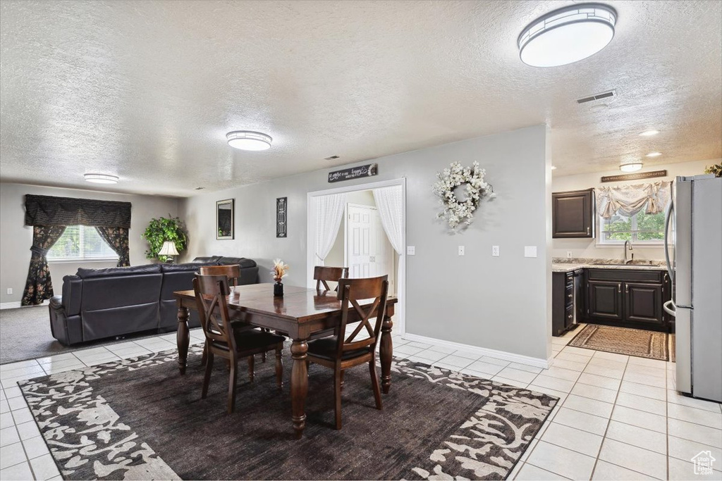 Dining space with light tile patterned flooring, a textured ceiling, visible vents, and baseboards