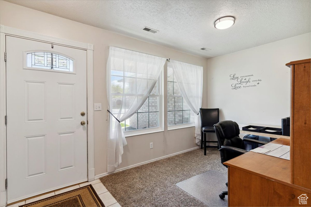 Office with baseboards, plenty of natural light, a textured ceiling, and visible vents