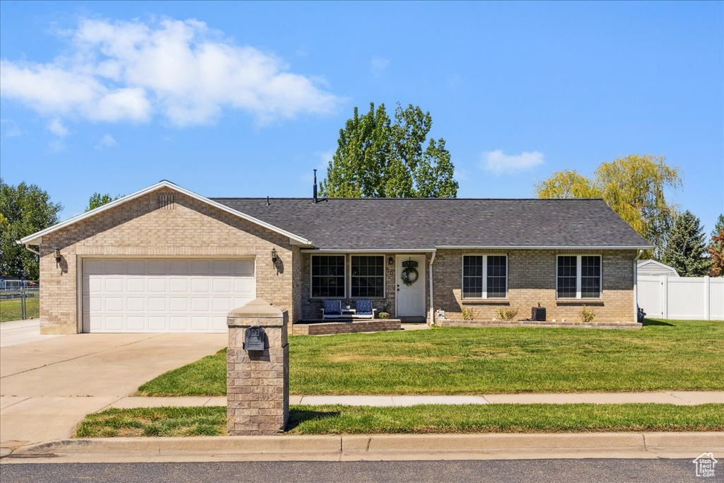 Ranch-style house with driveway, a front lawn, and brick siding