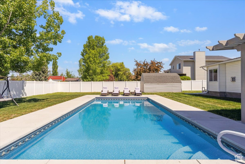 View of swimming pool featuring a yard, a fenced in pool, an outbuilding, and a fenced backyard