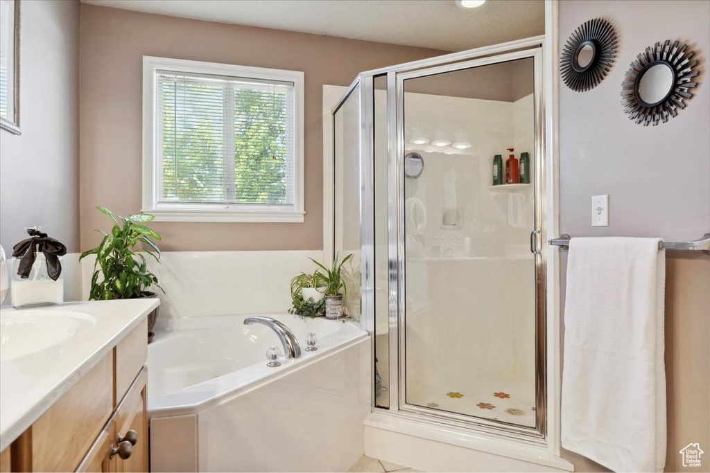 Bathroom featuring a shower stall, a bath, and vanity