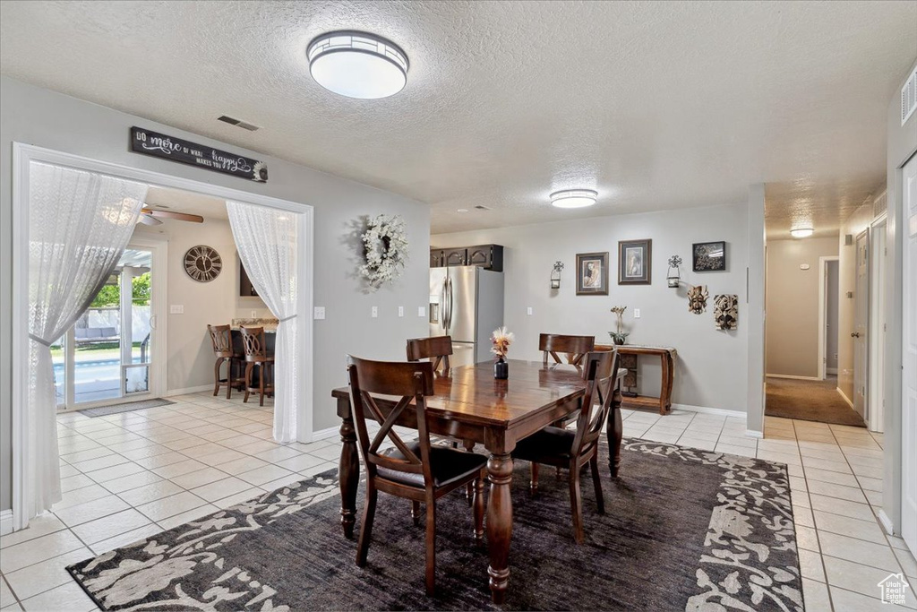 Dining room with visible vents, light tile patterned flooring, baseboards, ceiling fan, and a textured ceiling