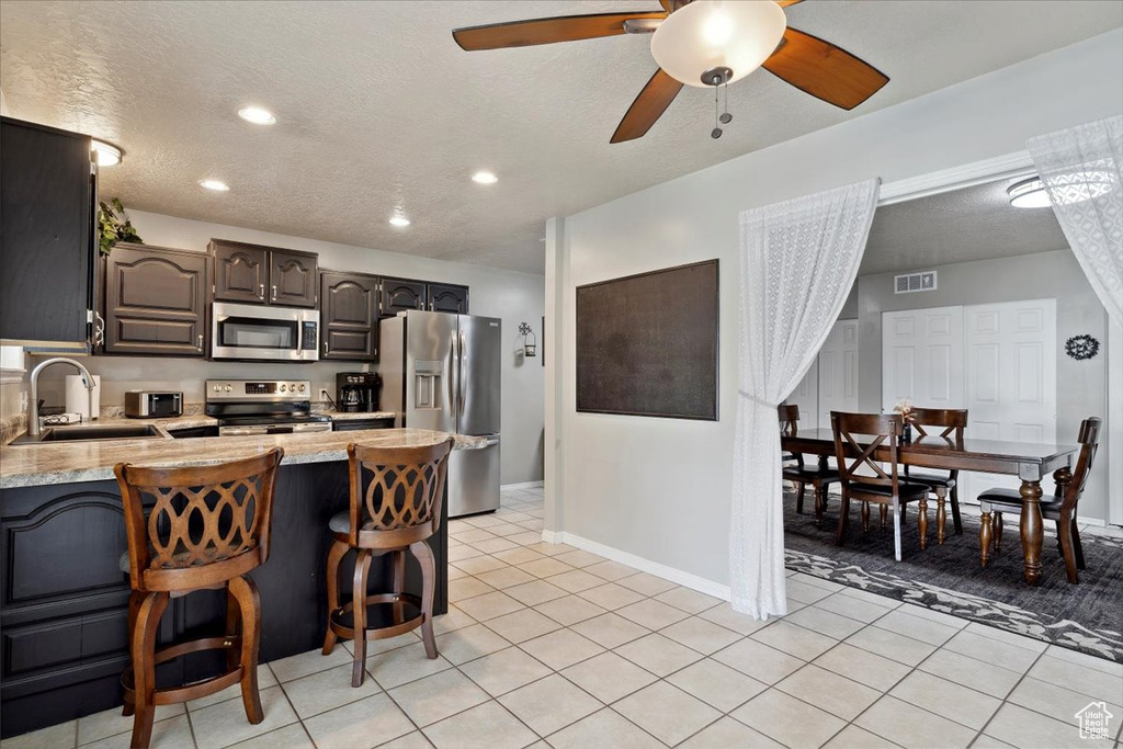 Kitchen featuring appliances with stainless steel finishes, a sink, light countertops, a peninsula, and light tile patterned flooring