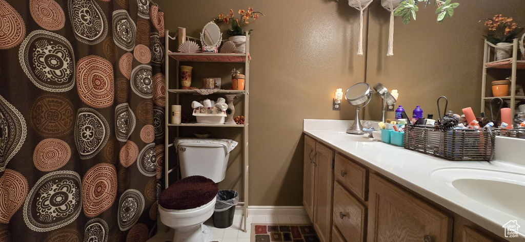 Bathroom featuring double vanity, baseboards, toilet, and a sink