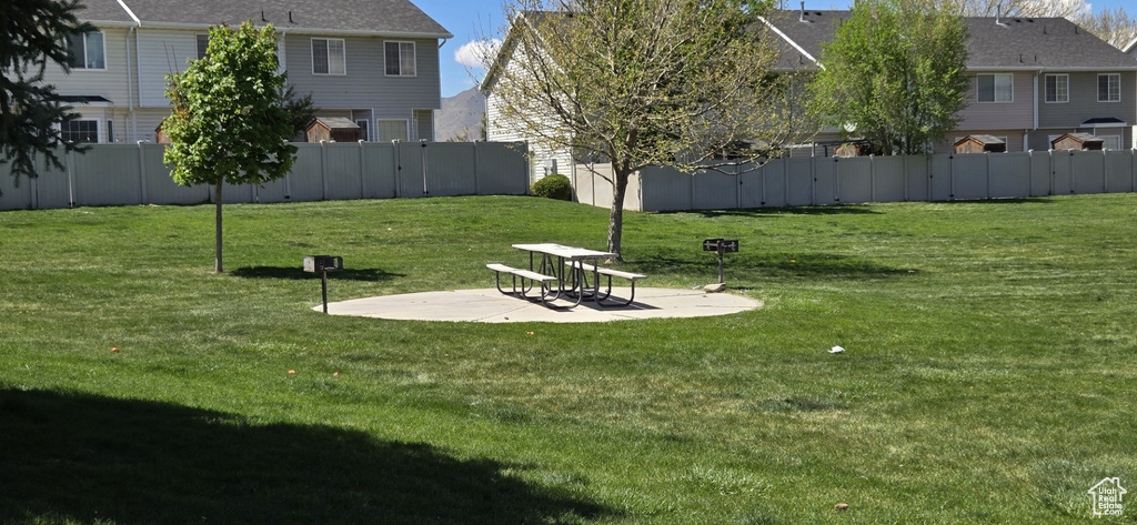 View of community with fence, a yard, and a patio area