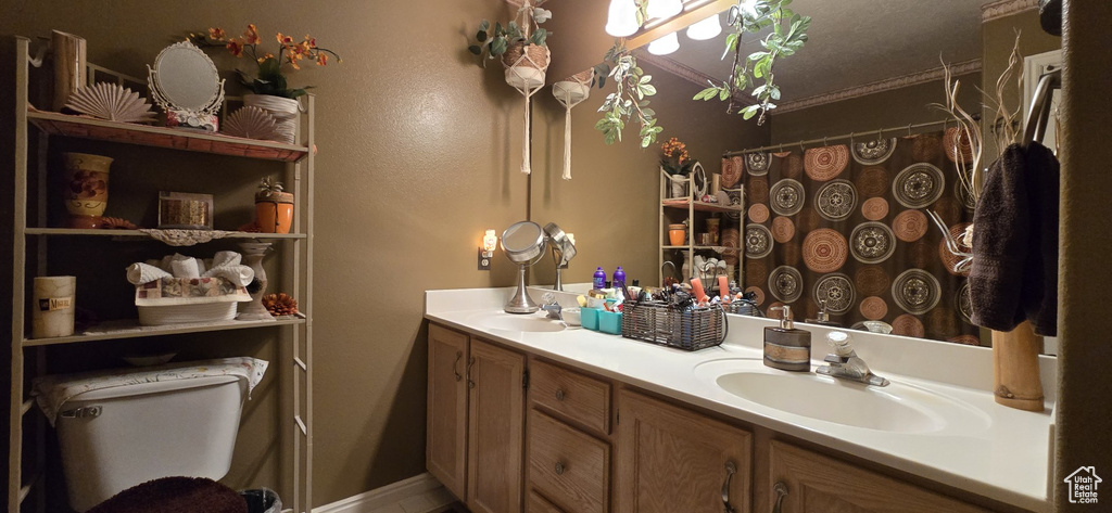 Bathroom featuring double vanity, a sink, curtained shower, and toilet