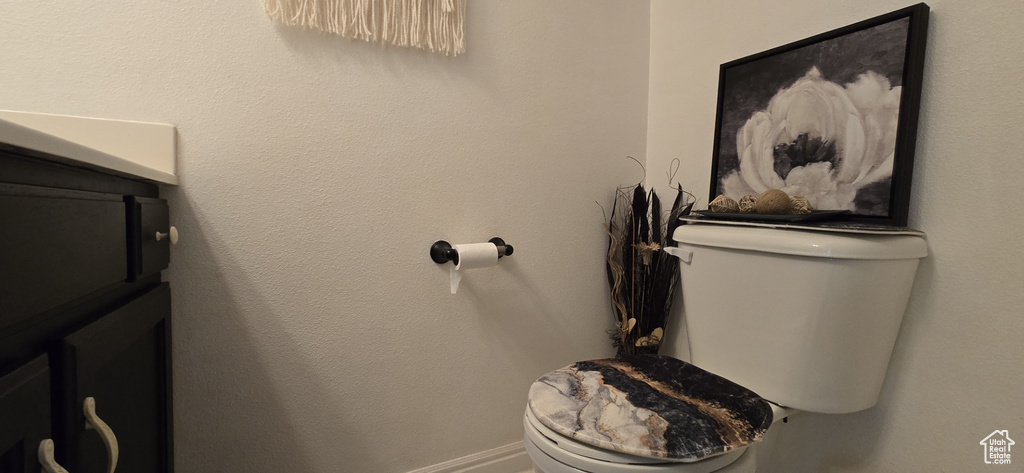 Half bathroom with vanity, baseboards, and toilet