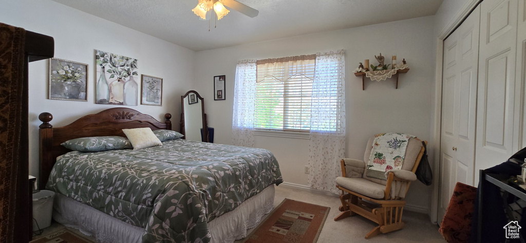 Carpeted bedroom featuring ceiling fan and a closet