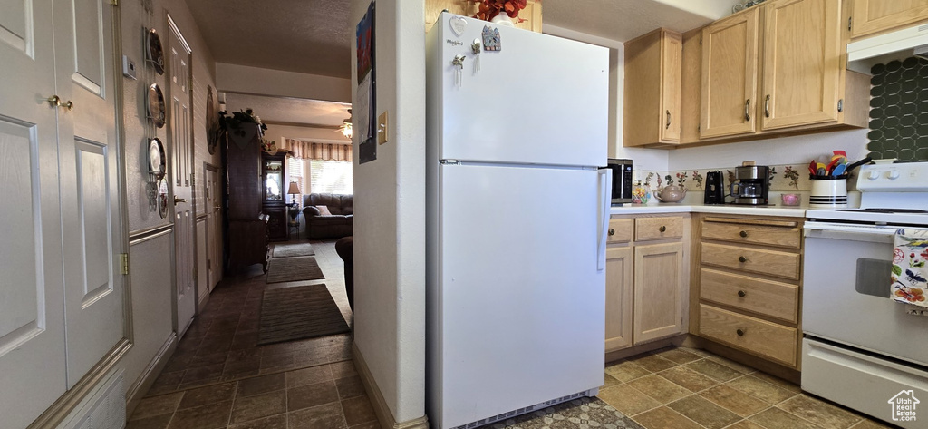 Kitchen featuring white appliances, light countertops, under cabinet range hood, and light brown cabinets