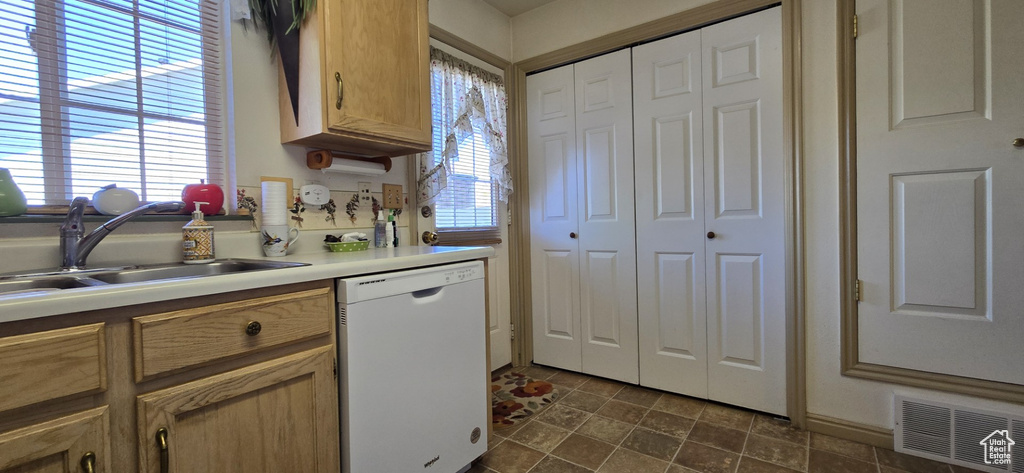 Kitchen featuring visible vents, white dishwasher, a sink, and light countertops