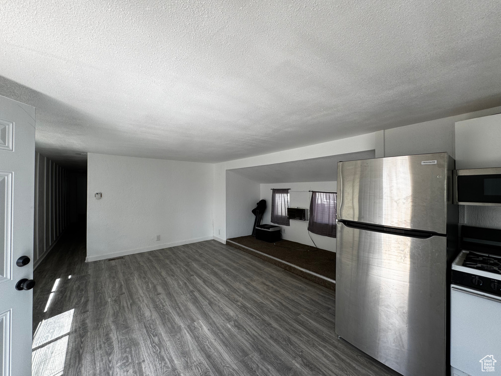 Kitchen with appliances with stainless steel finishes, baseboards, a textured ceiling, and wood finished floors