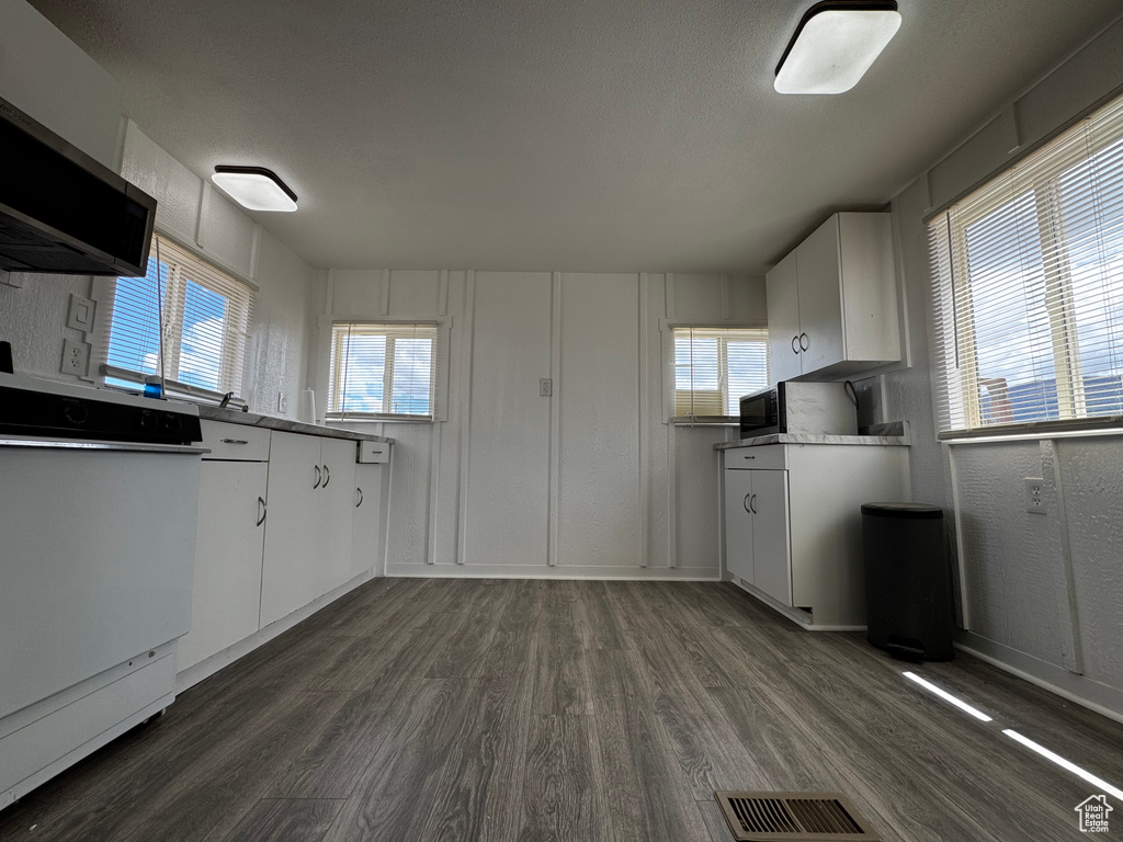 Kitchen with visible vents, dark wood-style flooring, and white cabinets