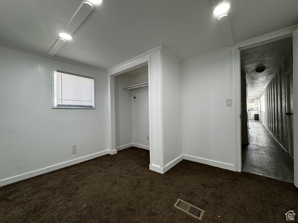 Unfurnished bedroom with a closet, baseboards, visible vents, and dark colored carpet