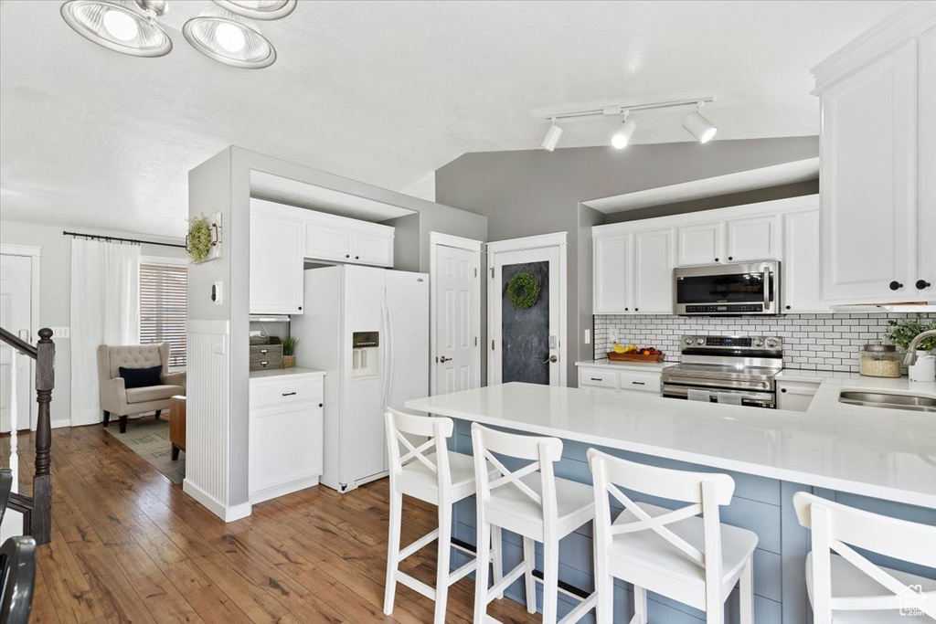 Kitchen featuring a sink, light countertops, stainless steel appliances, a peninsula, and tasteful backsplash