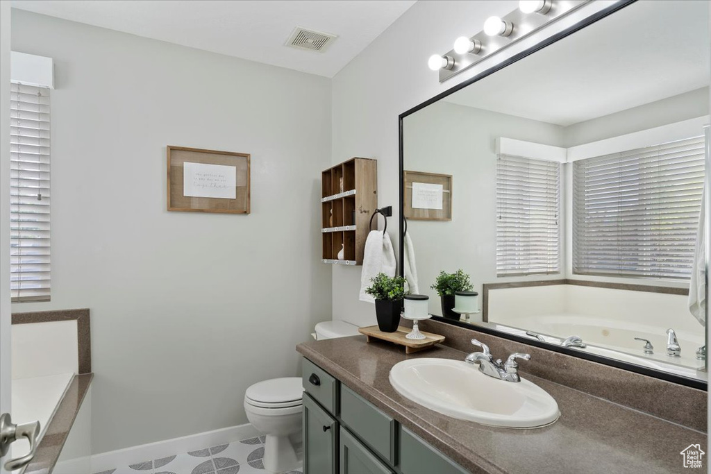 Full bathroom featuring vanity, toilet, baseboards, visible vents, and a bath