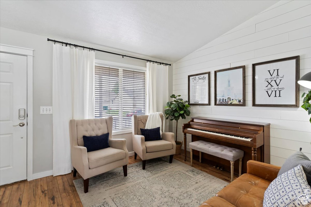 Sitting room featuring wood-type flooring, wooden walls, and vaulted ceiling