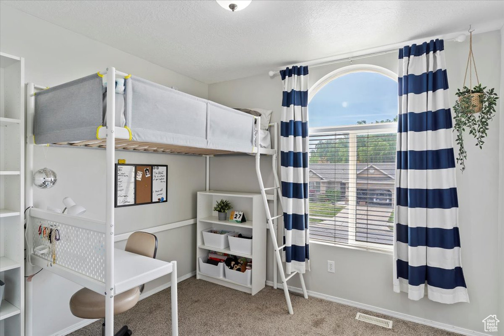 Carpeted bedroom featuring baseboards, a textured ceiling, and visible vents