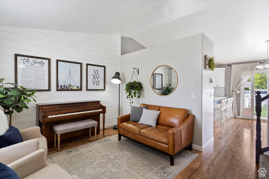 Living area with wooden walls, baseboards, hardwood / wood-style flooring, and lofted ceiling
